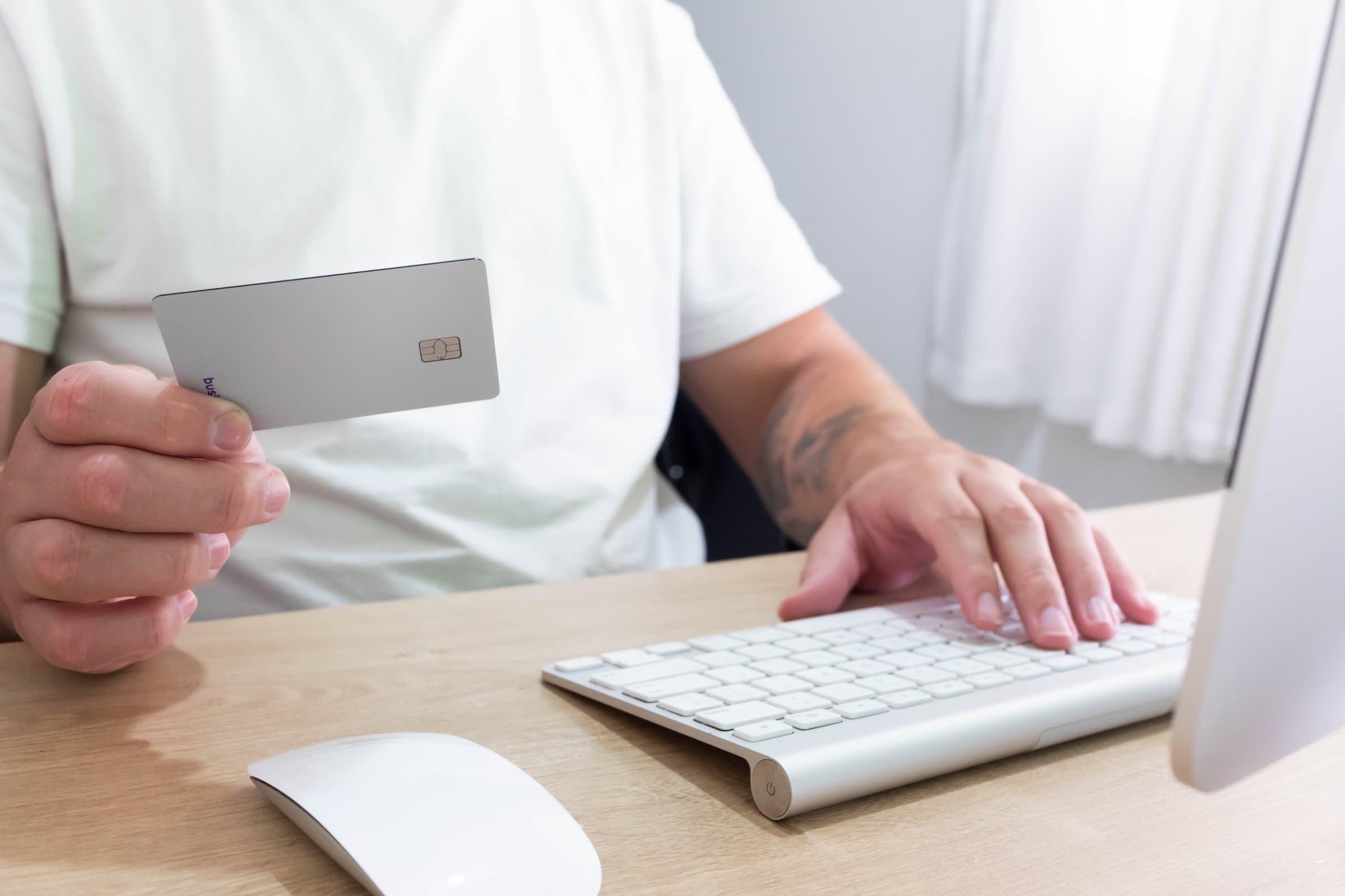 Person with a credit card using a laptop.