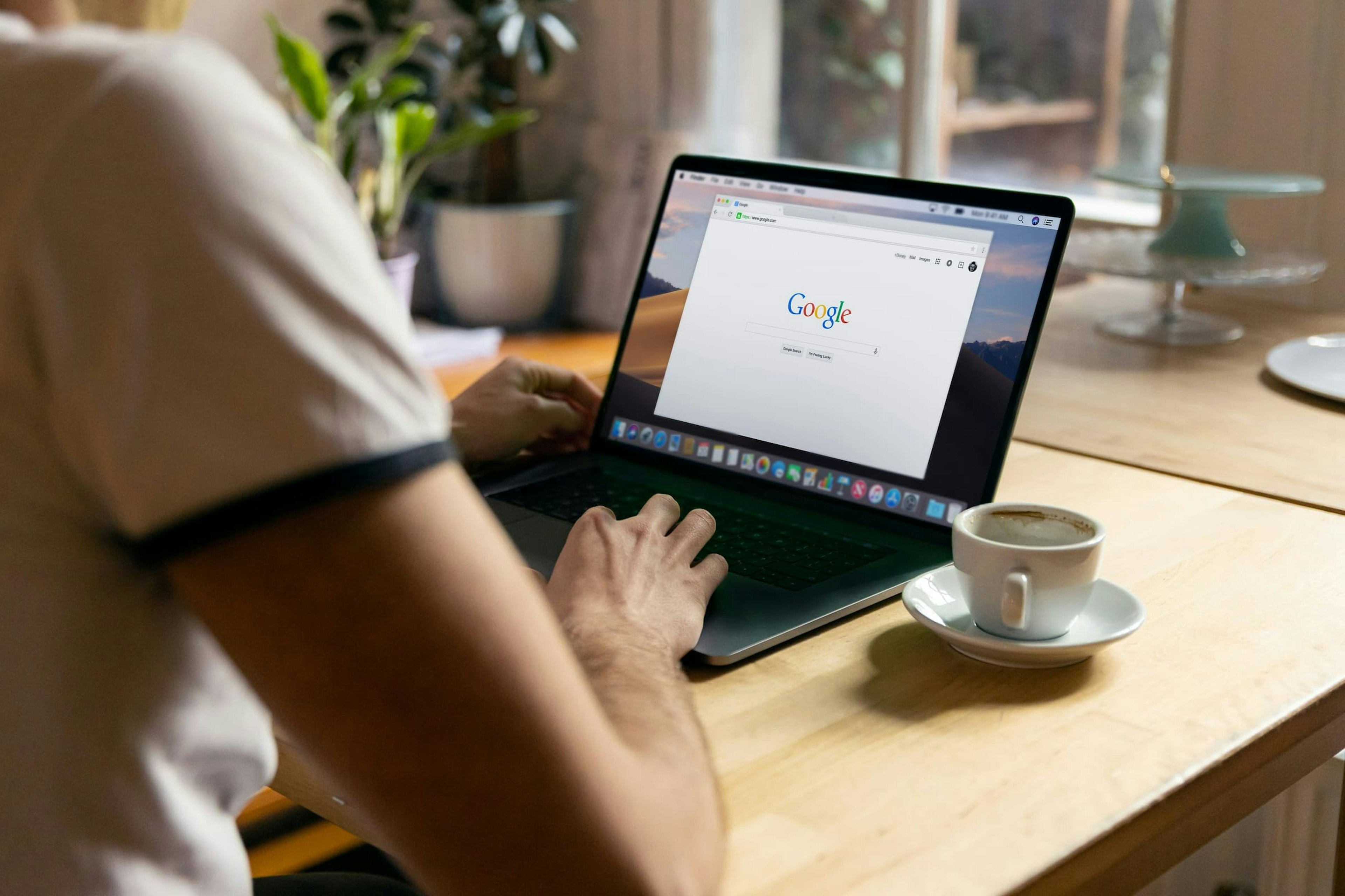 Man uses Apple MacBook in a cafe or restaurant searching Google website.