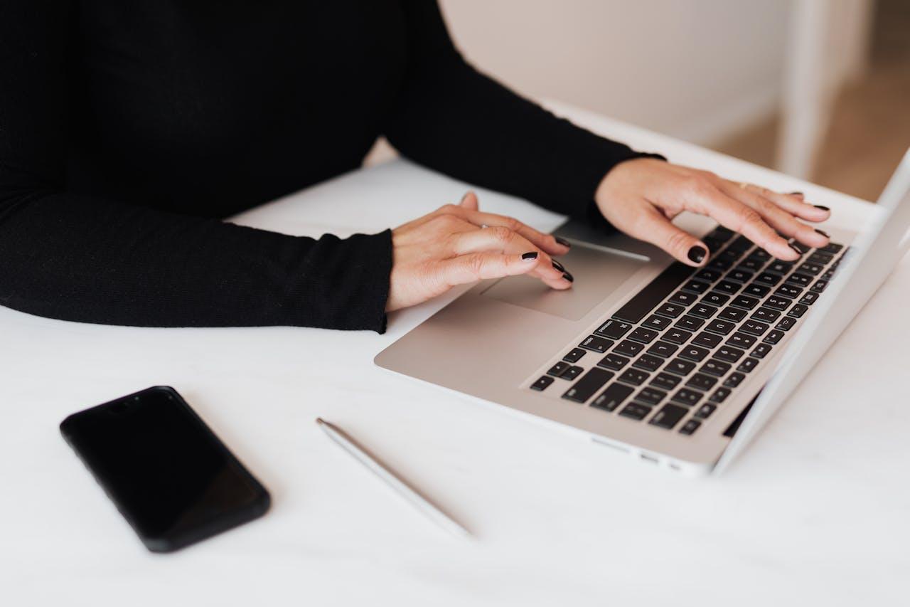 Image of a person sitting by a desk and in front of a computer